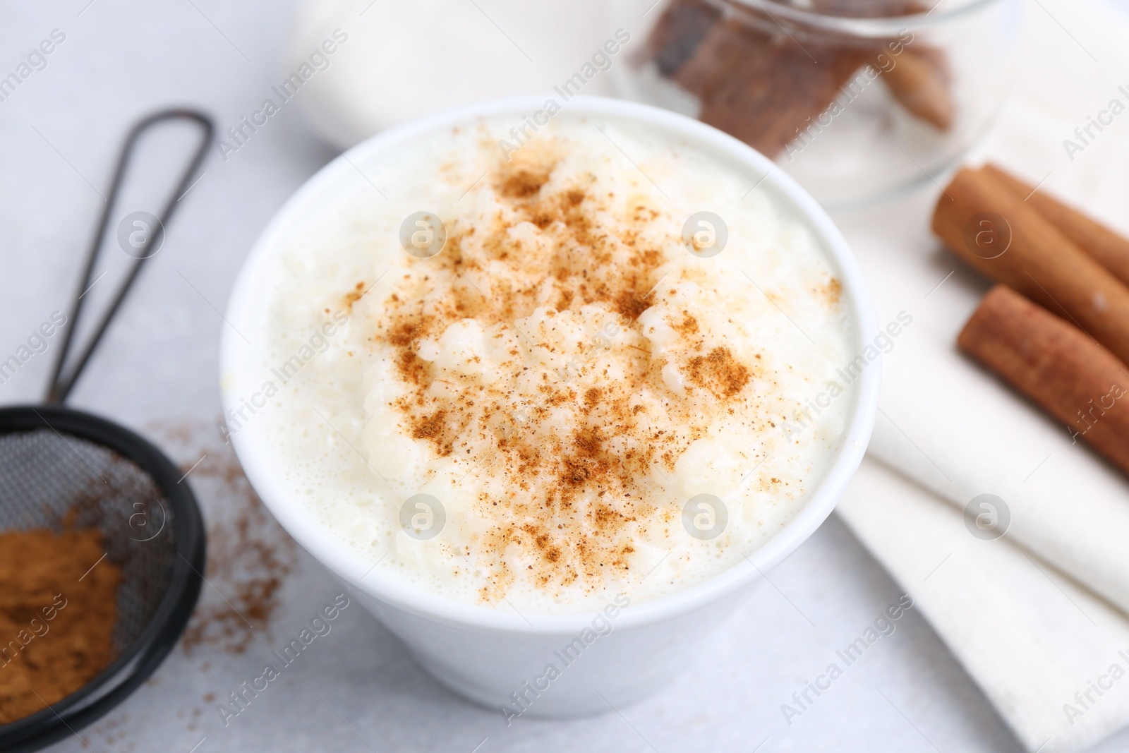 Photo of Delicious rice pudding with cinnamon on light table, closeup