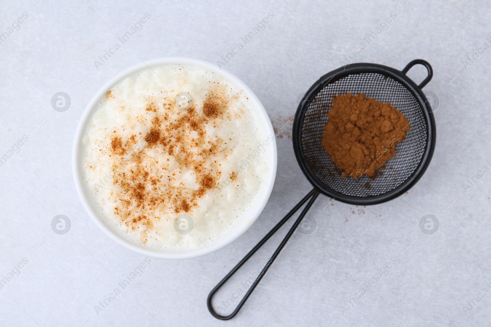 Photo of Delicious rice pudding with cinnamon on light table, top view