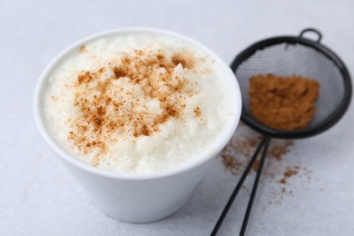 Photo of Delicious rice pudding with cinnamon on light table, closeup