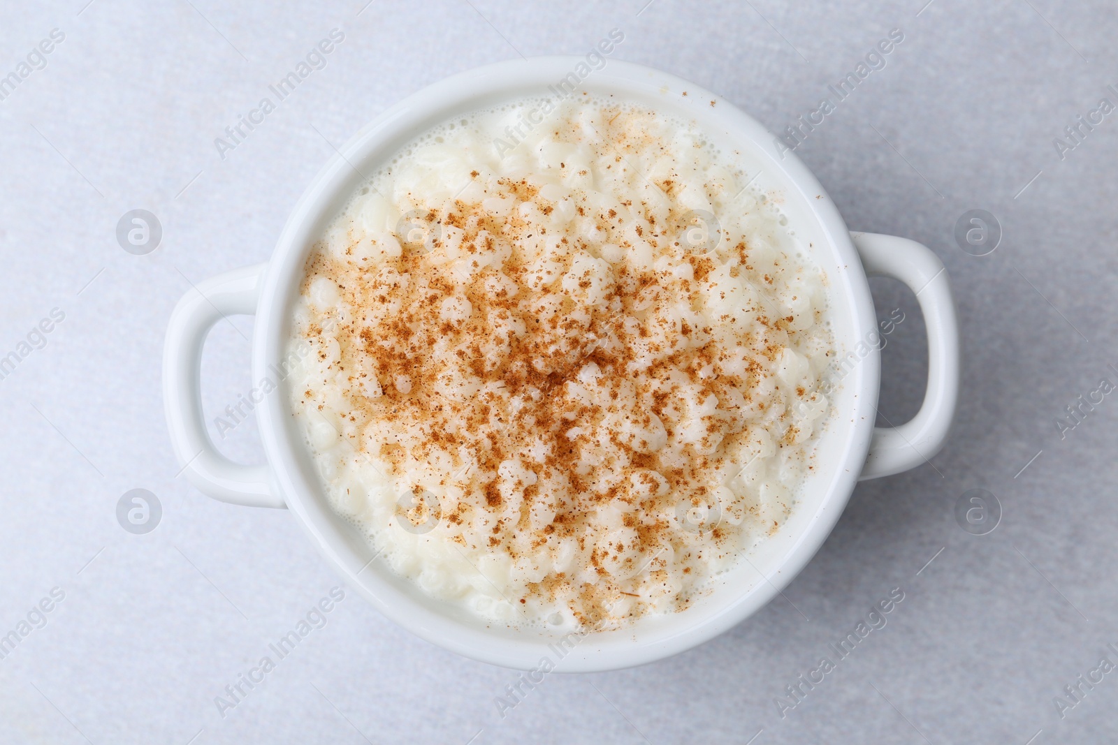 Photo of Delicious rice pudding with cinnamon on light table, top view