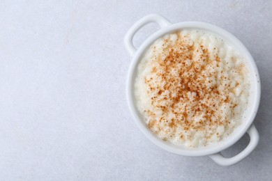 Photo of Delicious rice pudding with cinnamon on light table, top view. Space for text