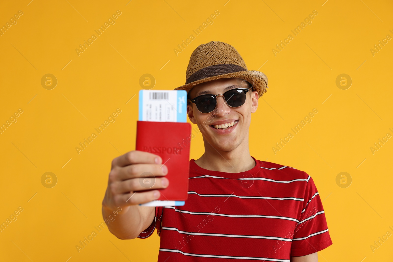 Photo of Happy traveller in sunglasses with passport and ticket on yellow background