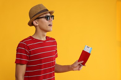 Photo of Traveller in sunglasses with passport and ticket on yellow background, space for text