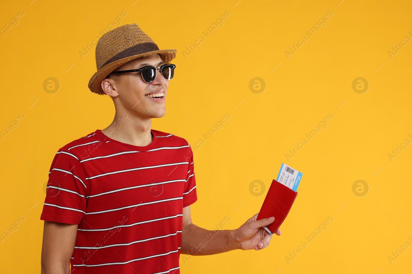 Photo of Happy traveller in sunglasses with passport and ticket on yellow background, space for text