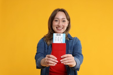 Photo of Happy traveller with passport and ticket on yellow background, selective focus