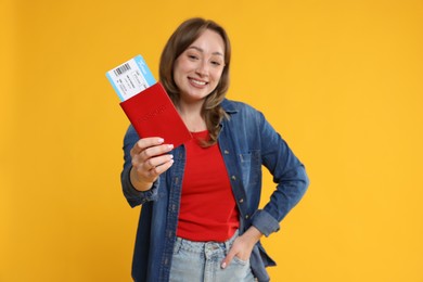 Photo of Happy traveller with passport and ticket on yellow background, selective focus