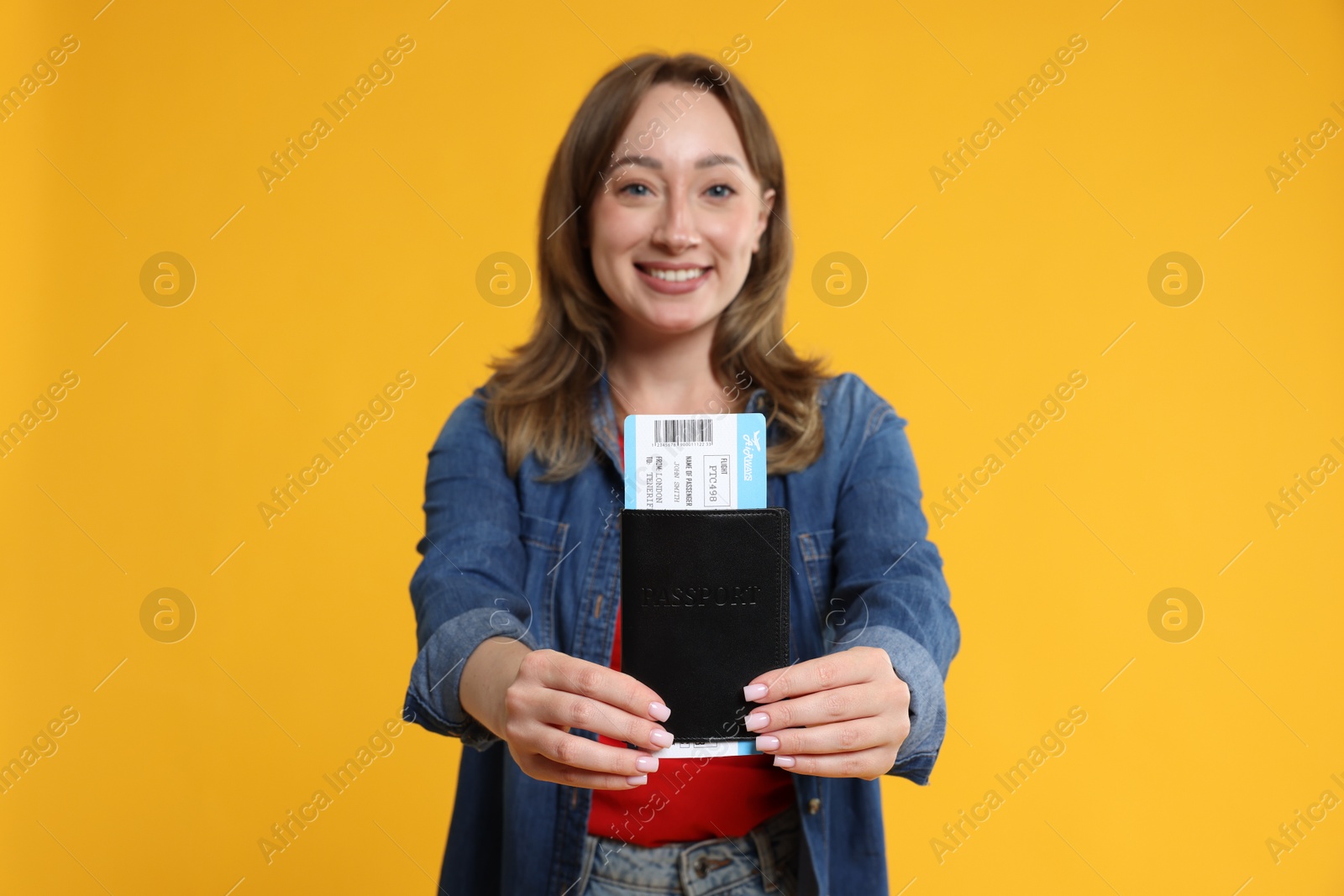 Photo of Happy traveller with passport and ticket on yellow background, selective focus