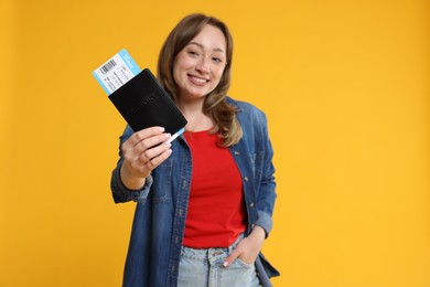 Photo of Happy traveller with passport and ticket on yellow background, selective focus