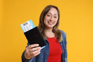 Photo of Happy traveller with passport and ticket on yellow background, selective focus