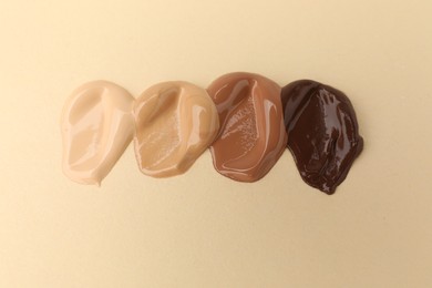 Photo of Samples of different foundations on beige background