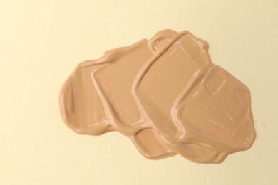 Photo of Sample of foundation on beige background, closeup