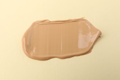 Photo of Sample of foundation on beige background, closeup