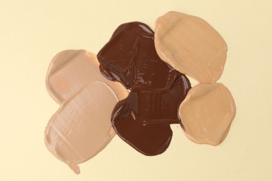 Photo of Samples of different foundations on beige background, above view