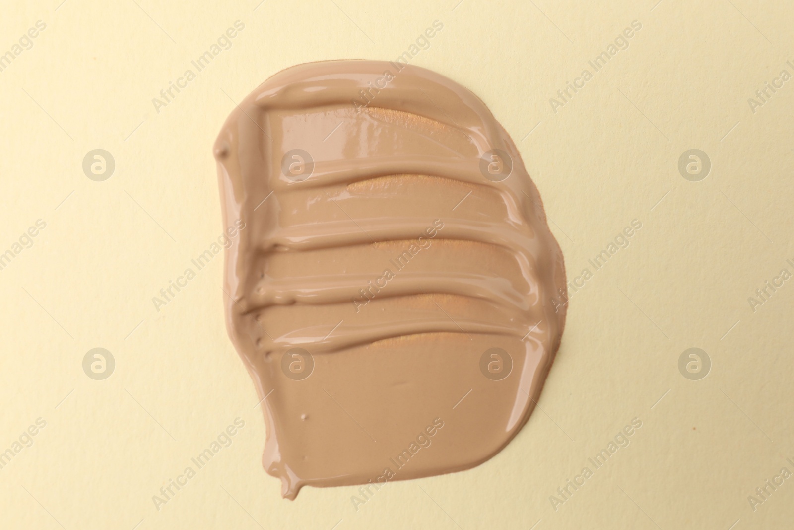 Photo of Sample of foundation on beige background, top view