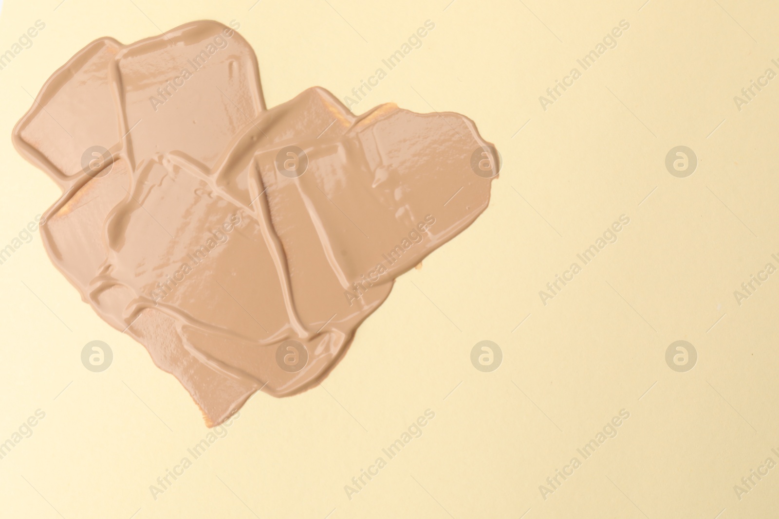 Photo of Sample of foundation on beige background, top view. Space for text