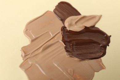 Photo of Samples of different foundations on beige background, closeup