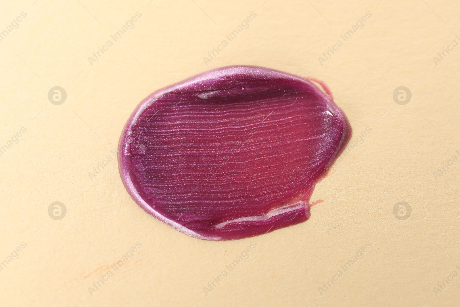 Photo of Sample of purple lipgloss on beige background, top view