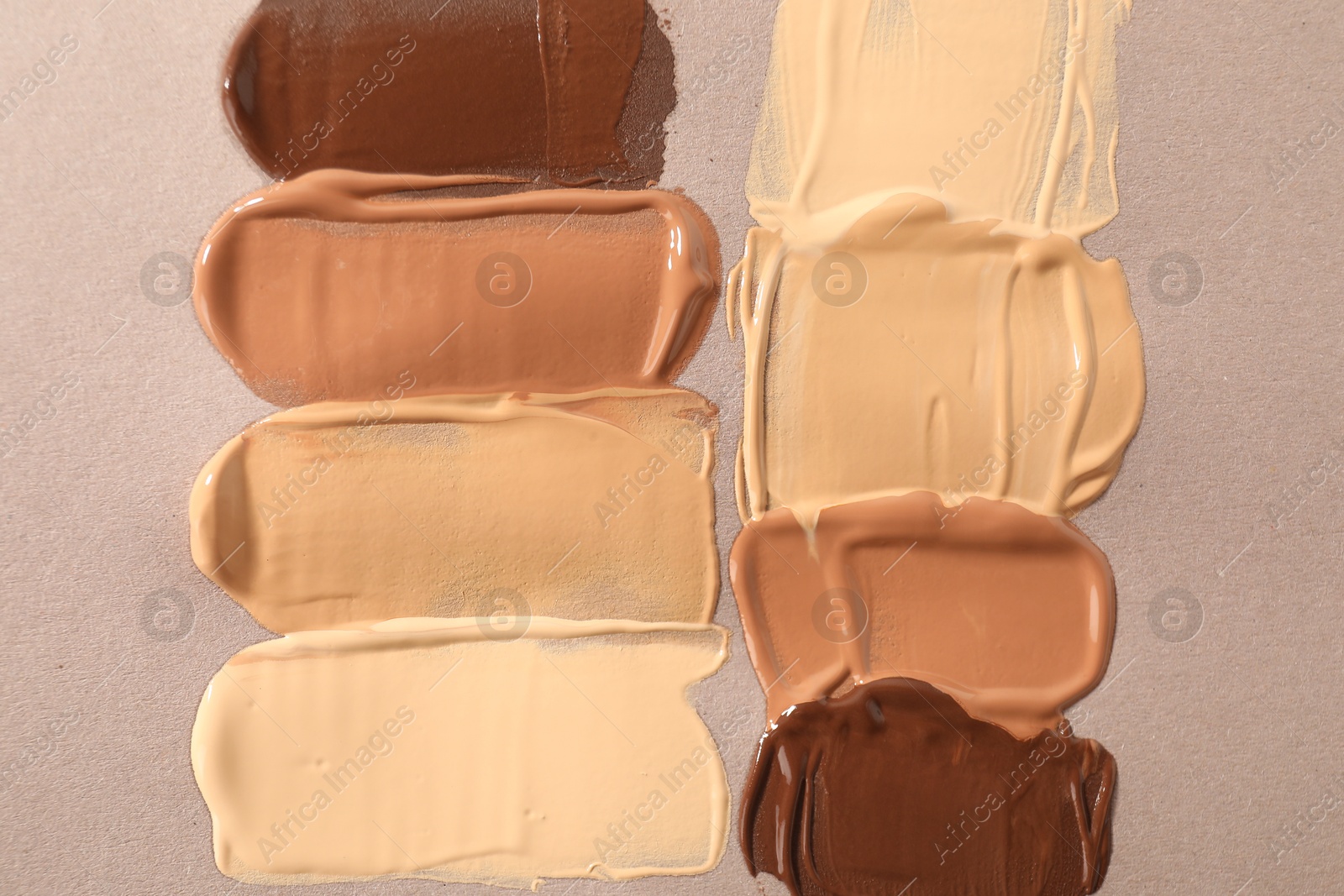 Photo of Samples of different foundations on beige background, top view