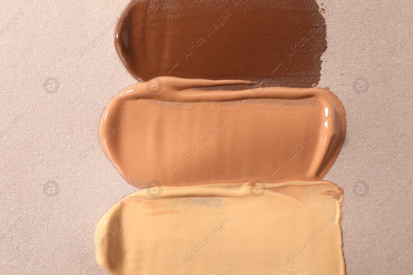 Photo of Samples of different foundations on beige background, top view