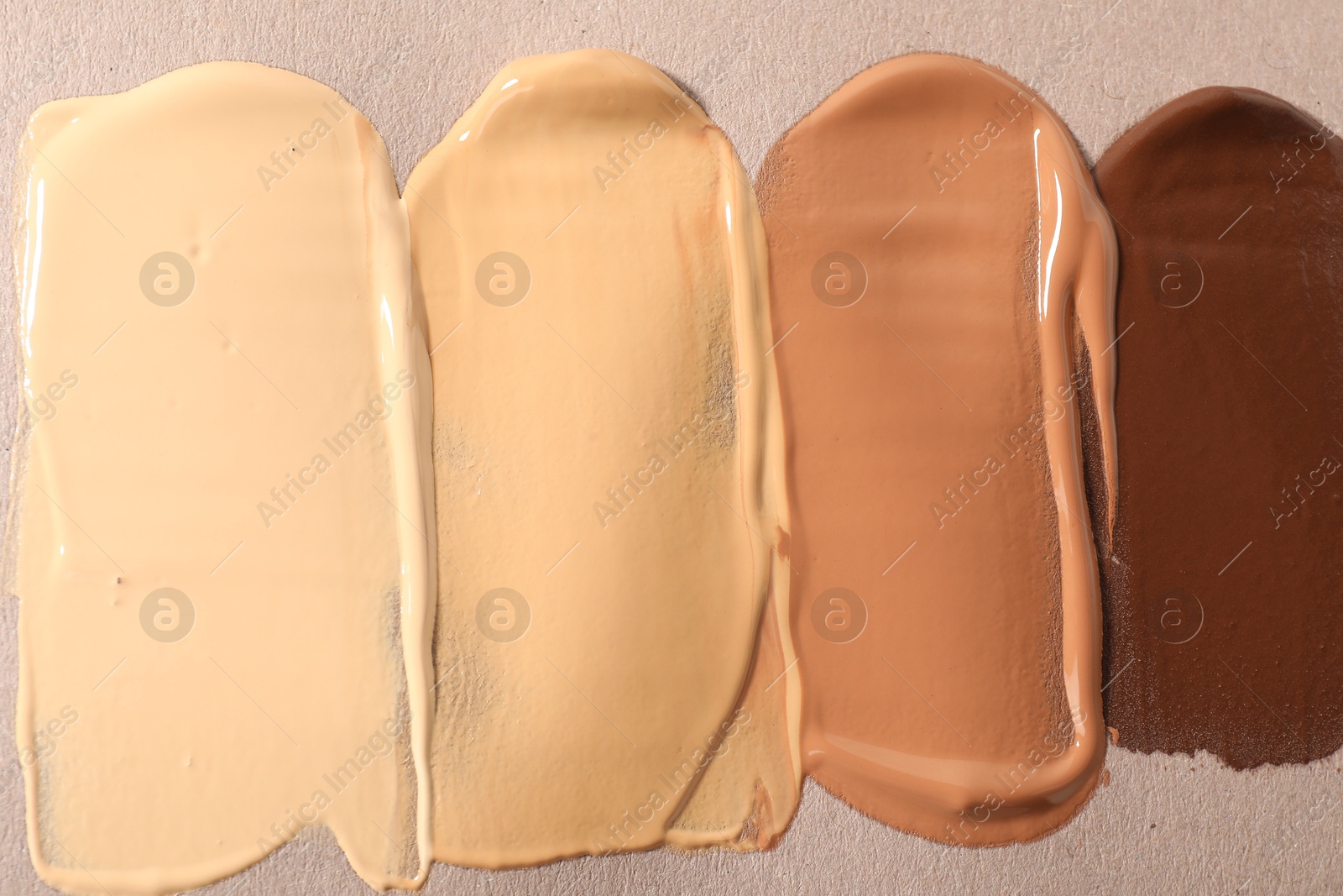 Photo of Samples of different foundations on beige background, top view