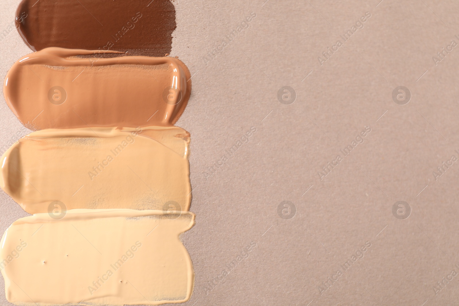 Photo of Samples of different foundations on beige background, top view. Space for text