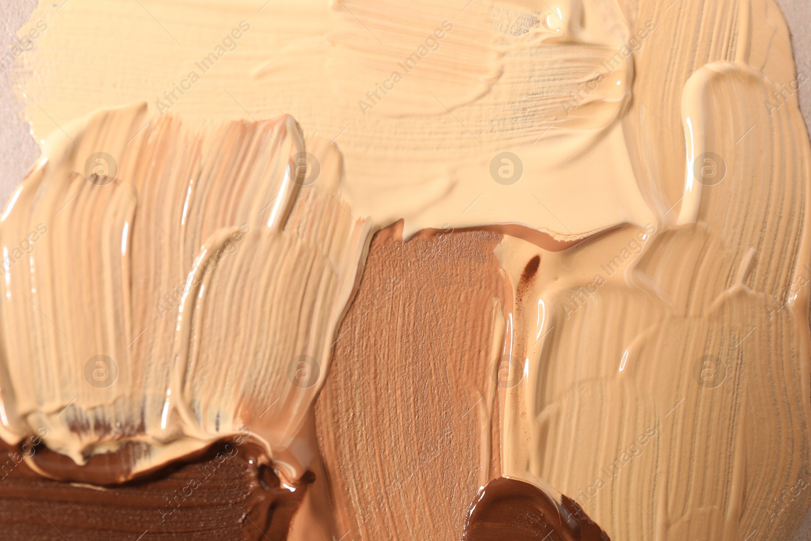 Photo of Samples of different foundations on beige background, top view