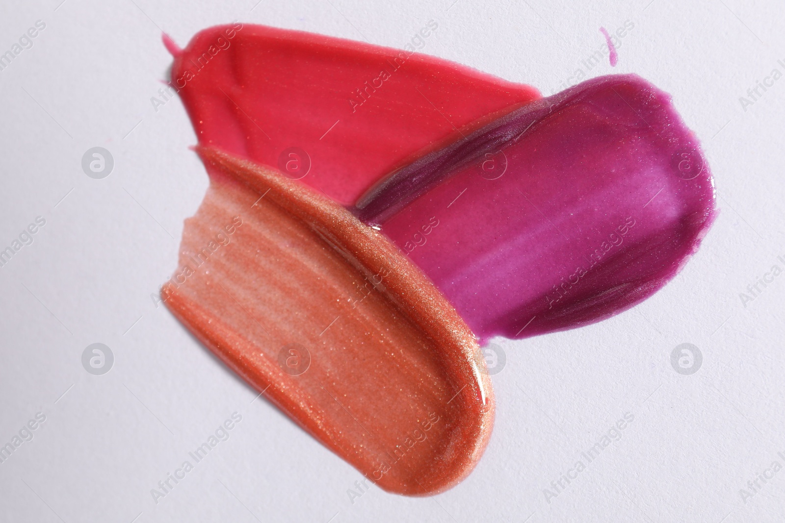 Photo of Samples of different lipglosses on light grey background, top view