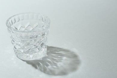 Photo of Beautiful crystal glass casting shadow on light background. Space for text