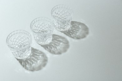 Photo of Beautiful crystal glasses casting shadows on light background