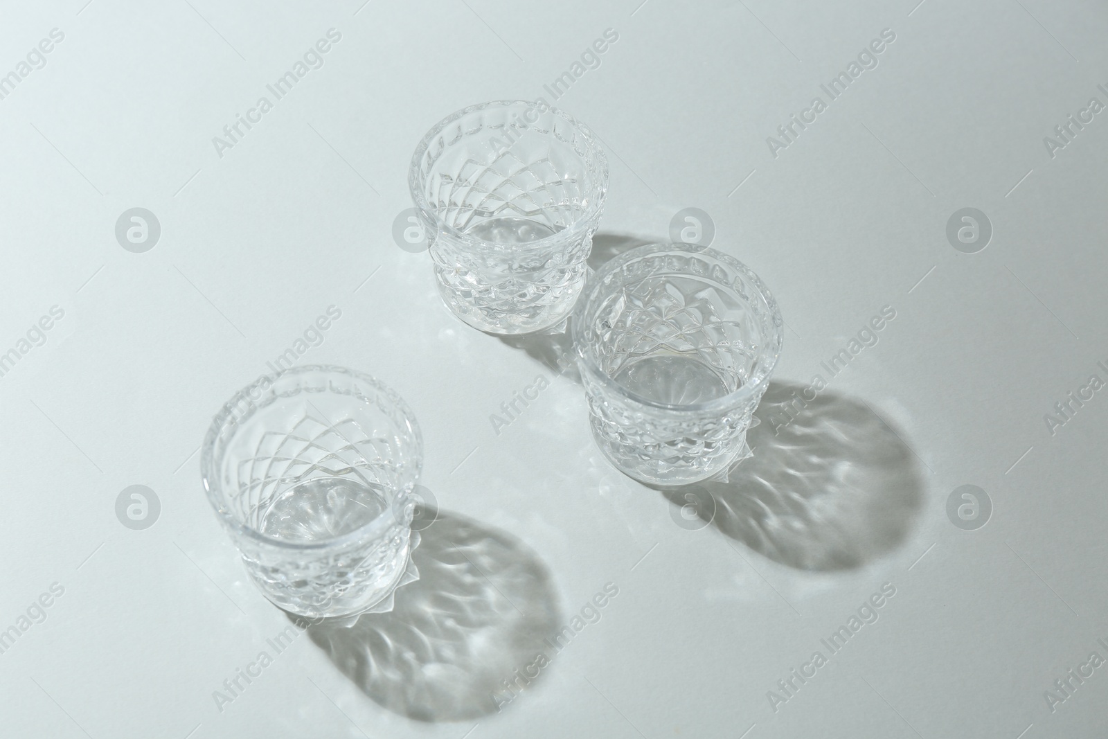 Photo of Beautiful crystal glasses casting shadows on light background