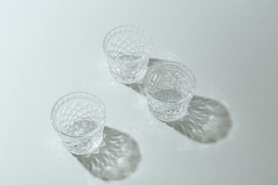 Photo of Beautiful crystal glasses casting shadows on light background