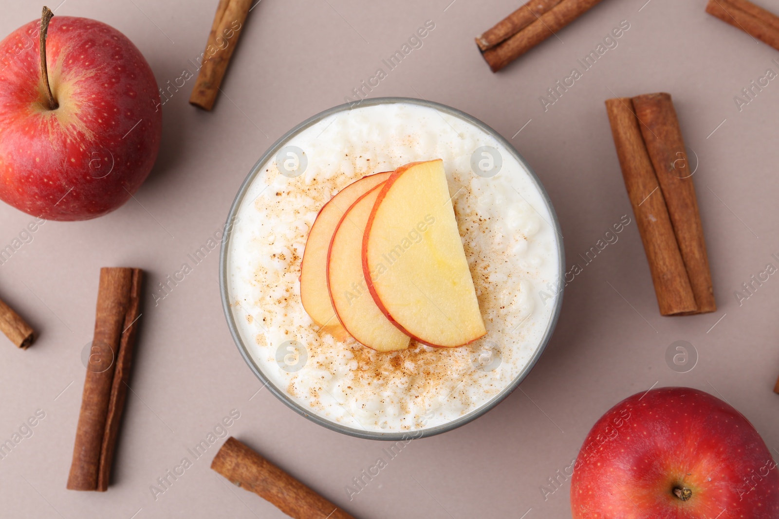 Photo of Delicious rice pudding with apples and cinnamon on color background, flat lay