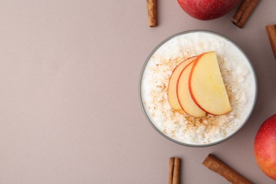 Photo of Delicious rice pudding with apples and cinnamon on color background, flat lay. Space for text