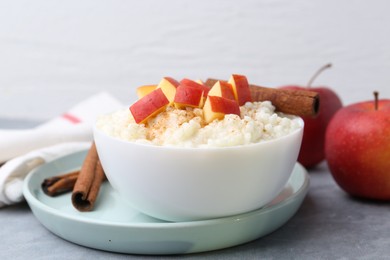 Photo of Delicious rice pudding with apples and cinnamon on grey table