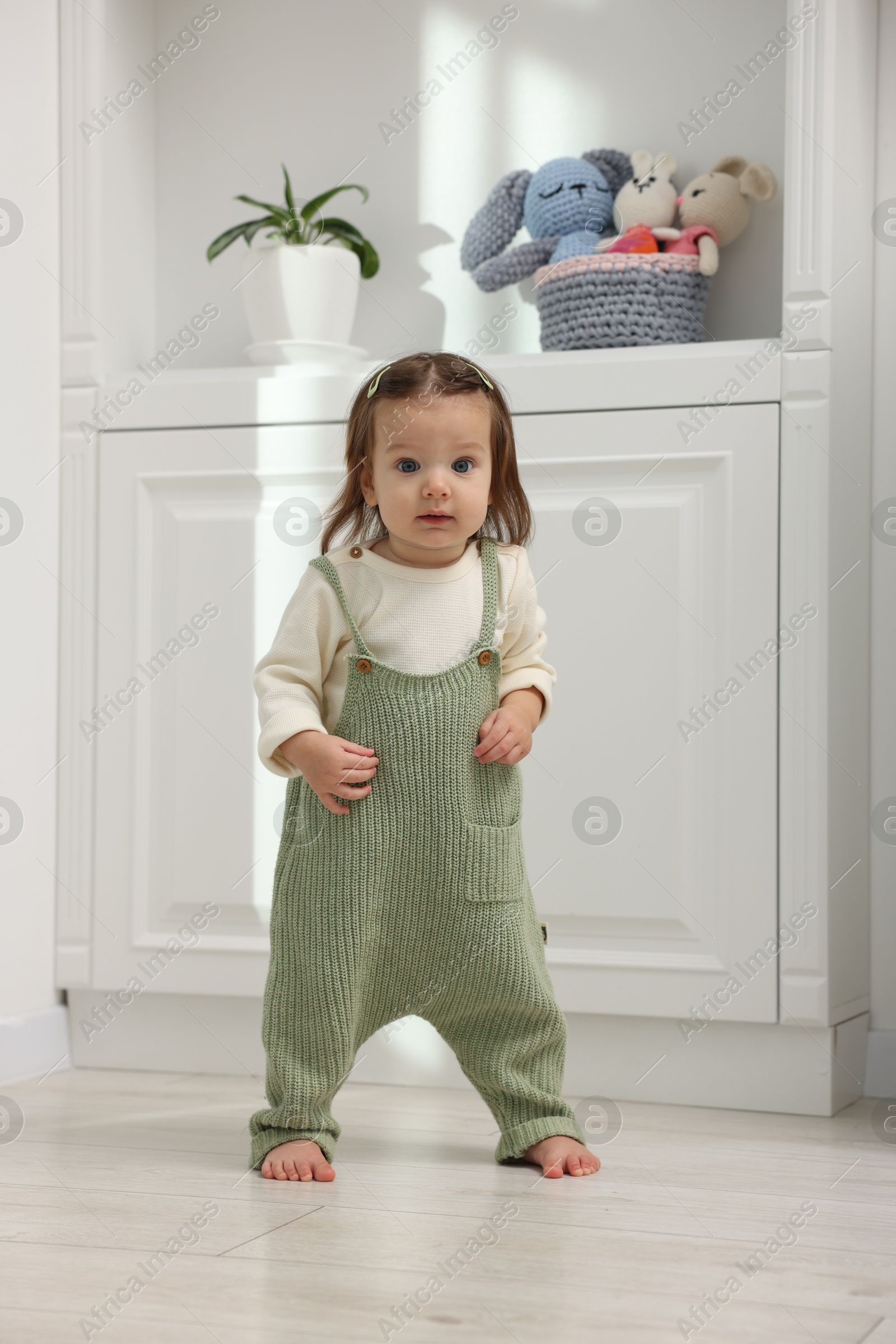 Photo of First steps. Cute little baby learning to walk at home