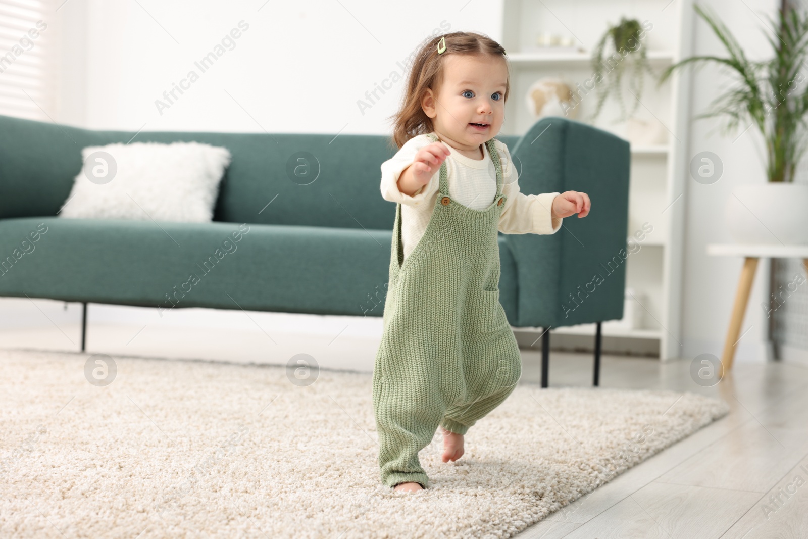 Photo of First steps. Cute little baby learning to walk at home