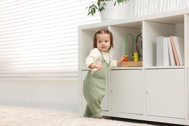 Photo of First steps. Cute little baby learning to walk at home, space for text