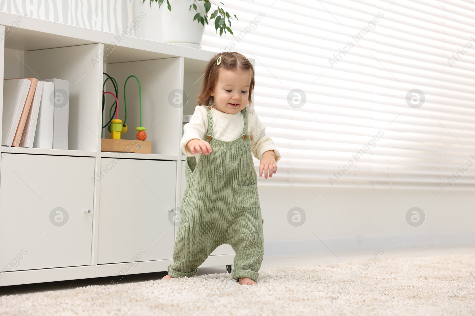 Photo of First steps. Cute little baby learning to walk at home, space for text