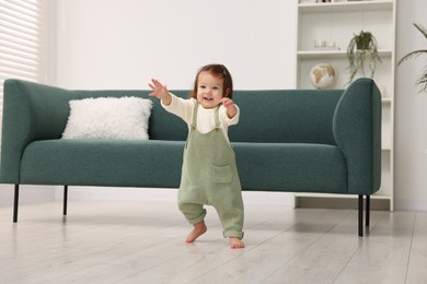 Photo of First steps. Cute little baby learning to walk at home