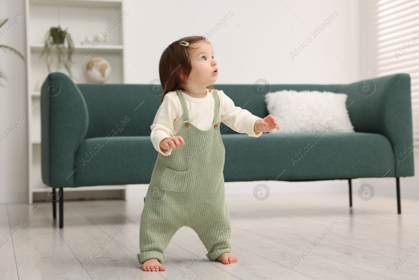 Photo of First steps. Cute little baby learning to walk at home