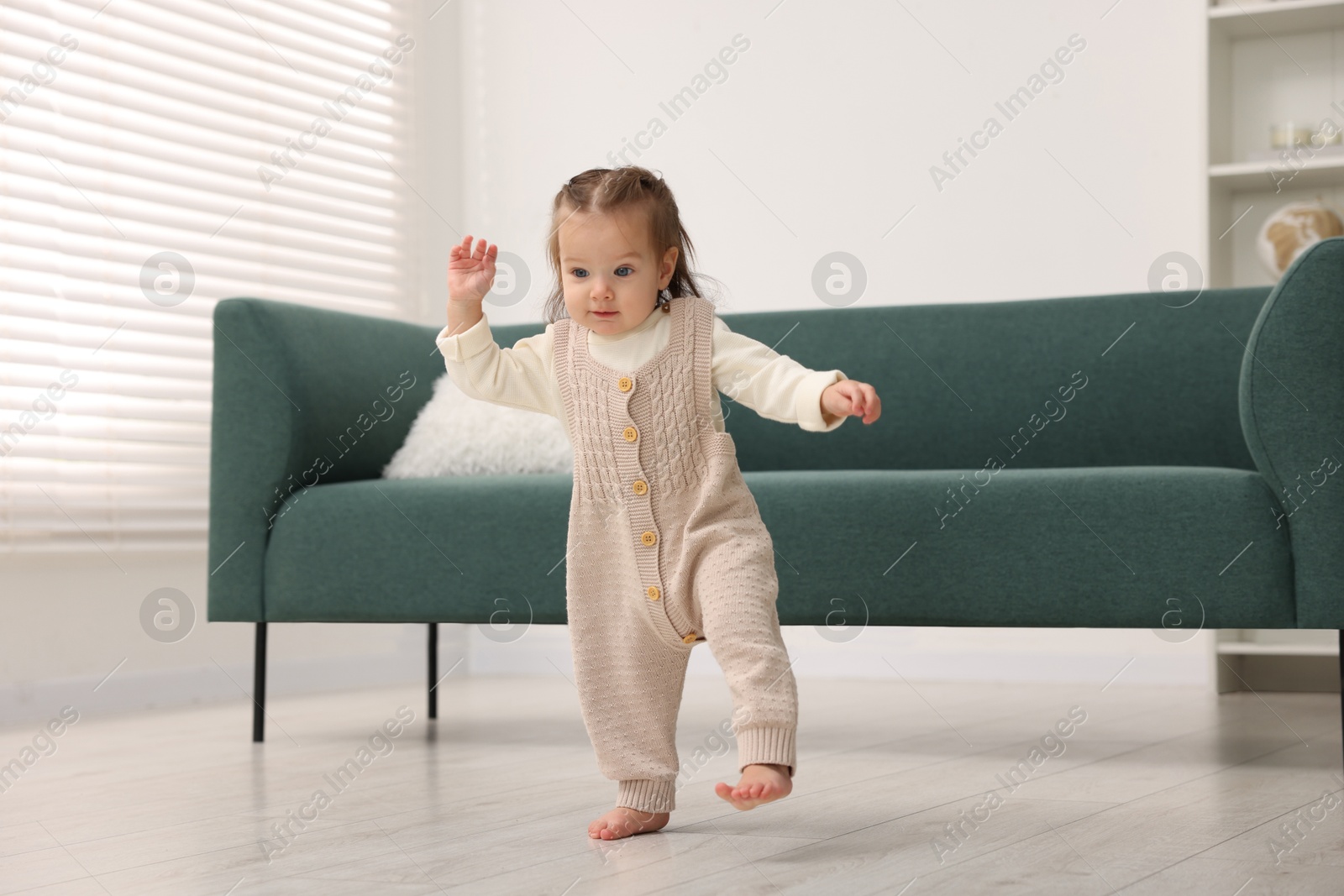 Photo of First steps. Cute little baby learning to walk at home