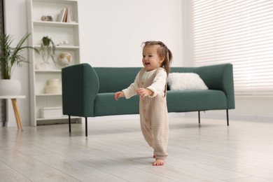 Photo of First steps. Cute little baby learning to walk at home