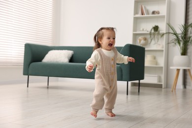 Photo of First steps. Cute little baby learning to walk at home