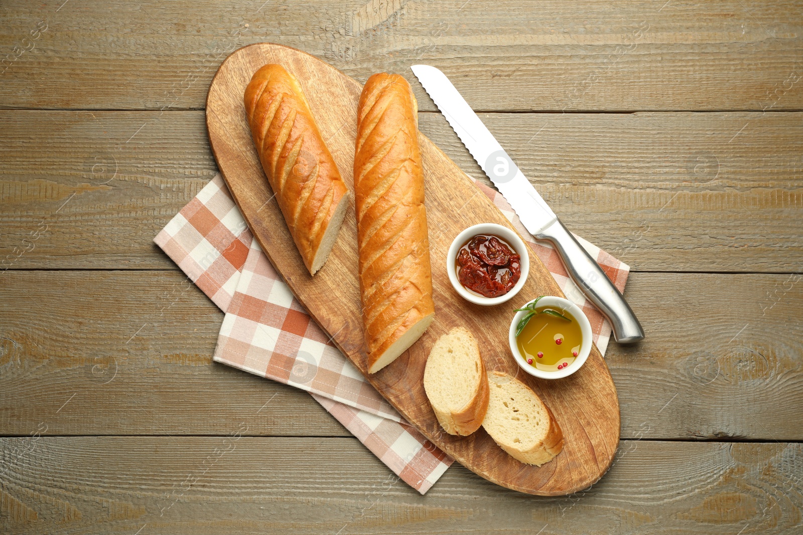 Photo of Cut fresh baguette served on wooden table, top view