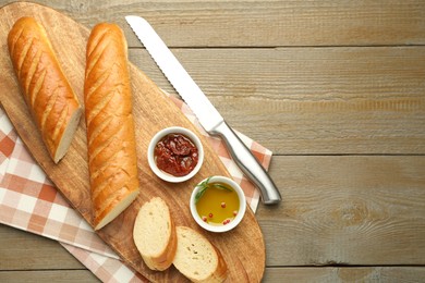 Photo of Cut fresh baguette served on wooden table, top view. Space for text