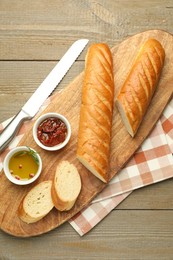 Photo of Cut fresh baguette served on wooden table, top view