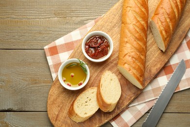 Photo of Cut fresh baguette served on wooden table, top view