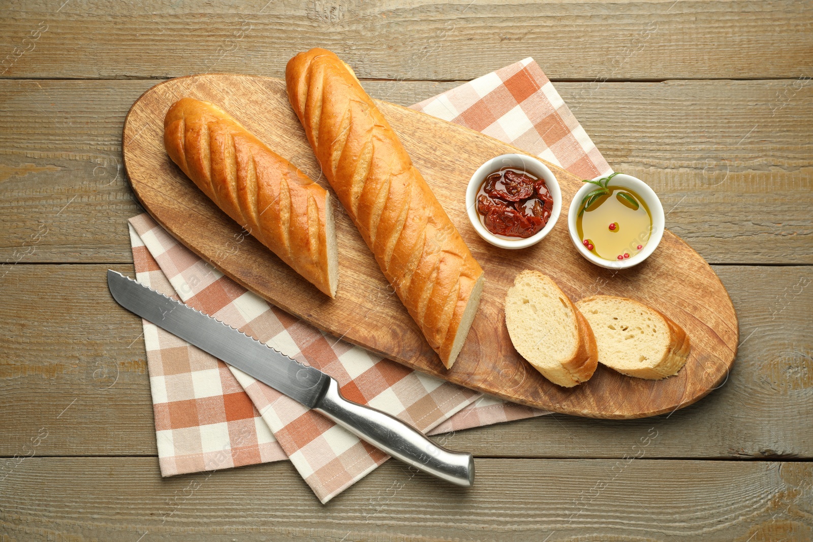 Photo of Cut fresh baguette served on wooden table, top view