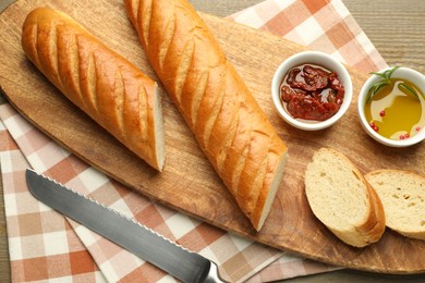 Photo of Cut fresh baguette served on wooden table, top view