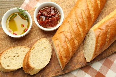 Photo of Cut fresh baguette served on wooden table, top view